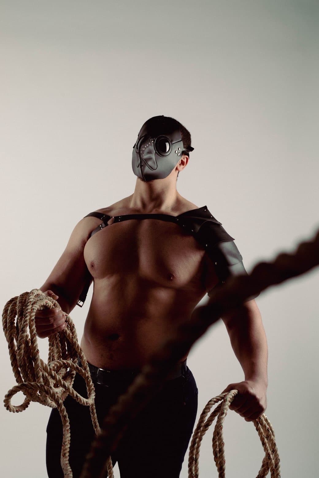 Masked studio portrait holding rope