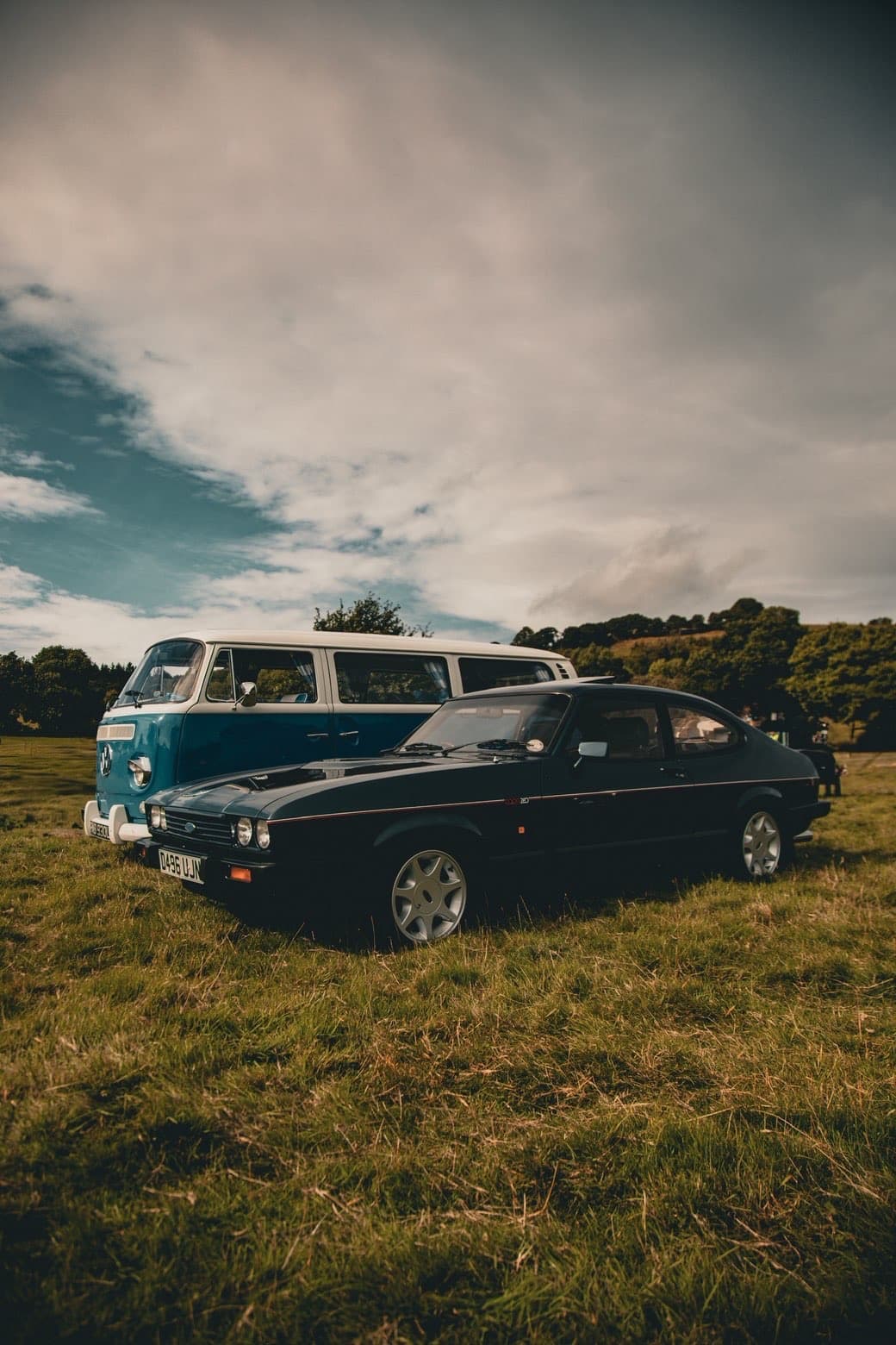 Classic car profile in a field beneath a bright sky